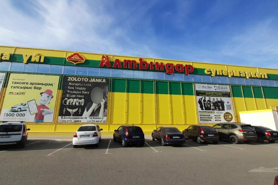 Altyndar supermarket in Kazakhstan: yellow and green facade with the Altyndar sign above the car park